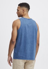 Blå bomulls tanktop med en avslappet passform, med rå kanter og rund utringning, brukt med lyse shorts.