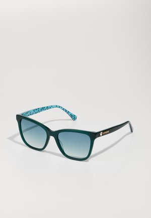 Green acetate sunglasses with a square frame, gradient lenses, and blue patterned temples. Features gold branding on the side.