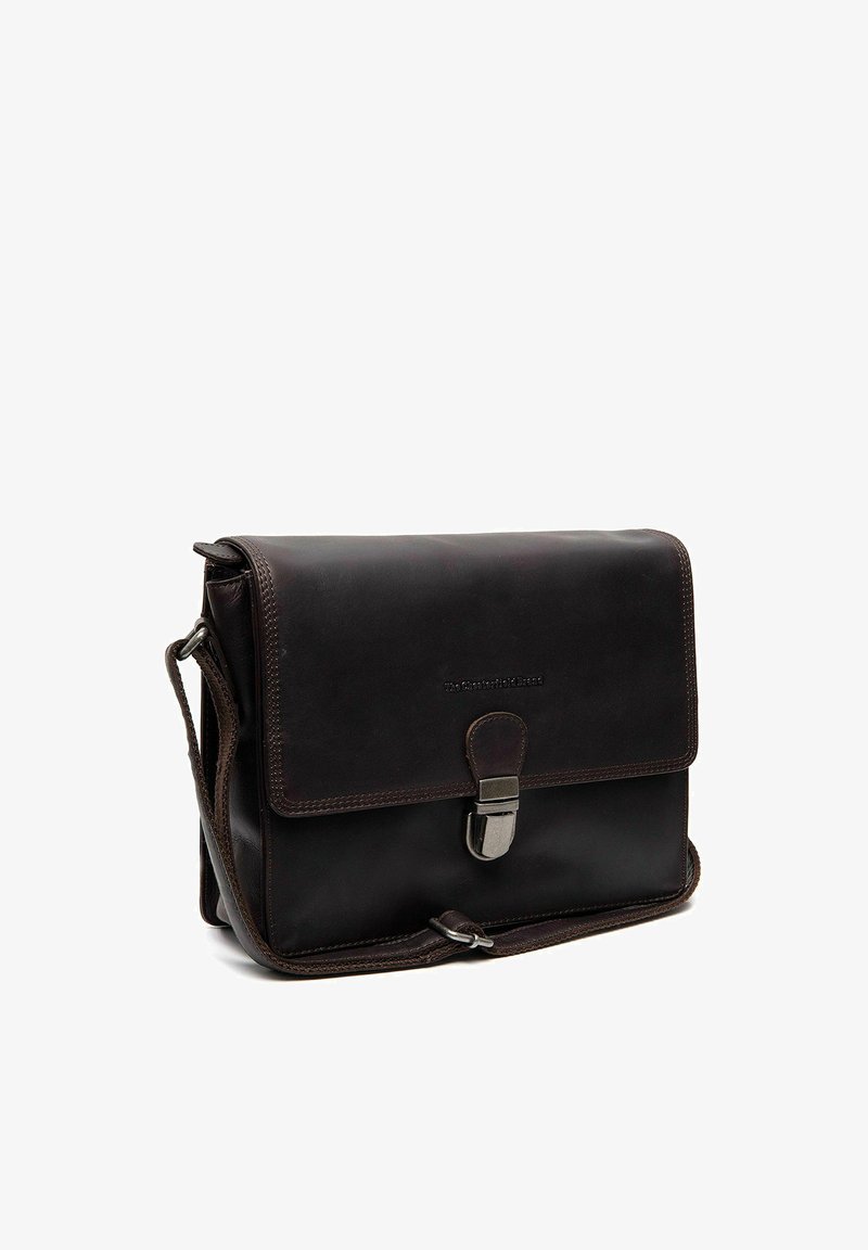 Sac messager en cuir marron foncé avec fermeture à boucle sur le devant et bandoulière réglable, présenté sur un fond blanc.