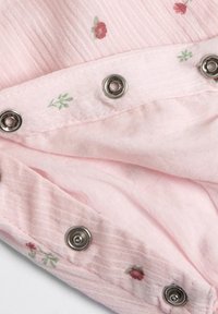 Tessuto rosa con sottili strisce testurizzate, caratterizzato da piccole ricami floreali e bottoni a pressione argentati lungo il bordo.