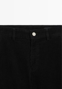 Zwarte corduroy broek met verticale ribbels, een zilveren knoopsluiting en een zijzak, die een gestructureerde stof en een verfijnd ontwerp toont.