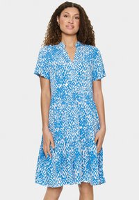 Blau-weißer gedruckter Kleid mit kurzen Ärmeln, V-Ausschnitt und geraffter Taille. Der Stoff hat eine gemusterte Textur und einen ausgestellten Rock.