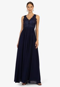 Navy blauw maxi-jurk met kant bodice en v-hals ontwerp, met een vloeiende rok en ingewikkelde bloemdetails op de schouders.