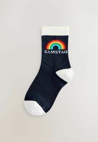 Calze di cotone blu navy con polsino e punta bianchi. Il design presenta una grafica arcobaleno e la parola "SAMSTAG" in bianco.