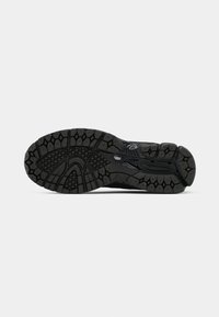 Semelle noire de chaussure de sport avec des rainures profondes et une adhérence texturée conçue pour la traction sur diverses surfaces.