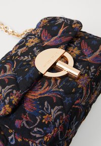 Töltött anyagú táska, multiszínű virágmintával, arany színű, kör alakú kapoccsal, melyre az "Vanessa Bruno" felirat van gravírozva, és arany lánc pánttal.