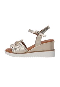 Metallic gold Wedge-Sandal mit geknotetem Detail, verstellbarem Knöchelriemen, brauner Innensohle und weißer, gerillter Außensohle.