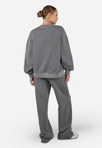 Grå oversized sweatshirt med dropped shoulders og ribbede manchetter, kombinert med matchende løs passform bukser, med en myk tekstur og uformell design.