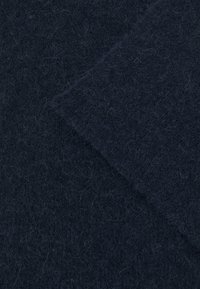Tissu en feutre de laine bleu marine foncé présentant une surface douce et texturée avec de fines fibres et un léger brillant, plié pour révéler des couches.
