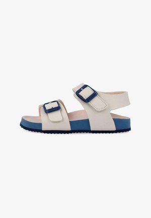 Sandalia de punta abierta blanca y azul con tiras ajustables y hebillas, suela plana, diseñada para uso casual.
