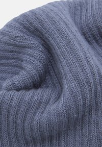 Berretto lavorato a maglia di colore azzurro chiaro, caratterizzato da costine verticali, texture morbida e una forma leggermente scossa. Il materiale sembra simile alla lana ed è accogliente.