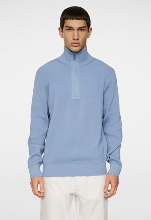 Ljust blå ribbad tröja med halvdragkedja, lång ärm och strukturerad tyg. Åtsittande design med en enfärgad yta och minimal detaljering.