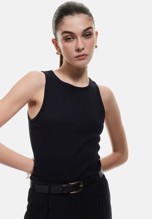 Top de tirantes negro con cuello redondo y diseño sin mangas, combinado con un cinturón negro con hebilla dorada y textura suave.