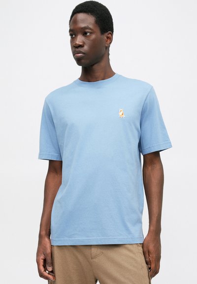 Ανοιχτό μπλε βαμβακερό μπλουζάκι με στρογγυλή λαιμόκοψη και κοντά μανίκια, με μικρή κεντημένη εικόνα αλεπούς στο αριστερό μέρος του στήθους.