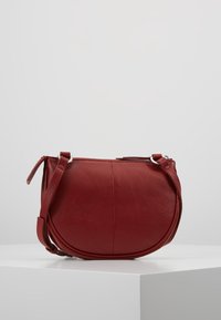 Czerwona skórzana torebka na ramię o zaokrąglonym kształcie, z regulowanym paskiem i zamkiem błyskawicznym. Teksturowana powierzchnia i subtelne przeszycia.