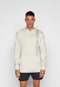 Gaišbeidzis puloveris ar kapuci, izgatavots no gludas auduma, ar priekšējām kangaroo kabatām, sānu svītrām un vilkšanas kapuci ar metāla akcentiem.