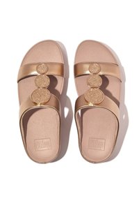 Metallic gouden slippers met drie cirkelvormige, gestructureerde accenten en brede banden. Zachte beige voetbed met een geperforeerde oppervlakte.