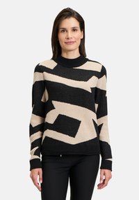 Knit sweater features a black base with beige abstract patterns, crew neck, and long sleeves. Textured fabric adds visual interest.