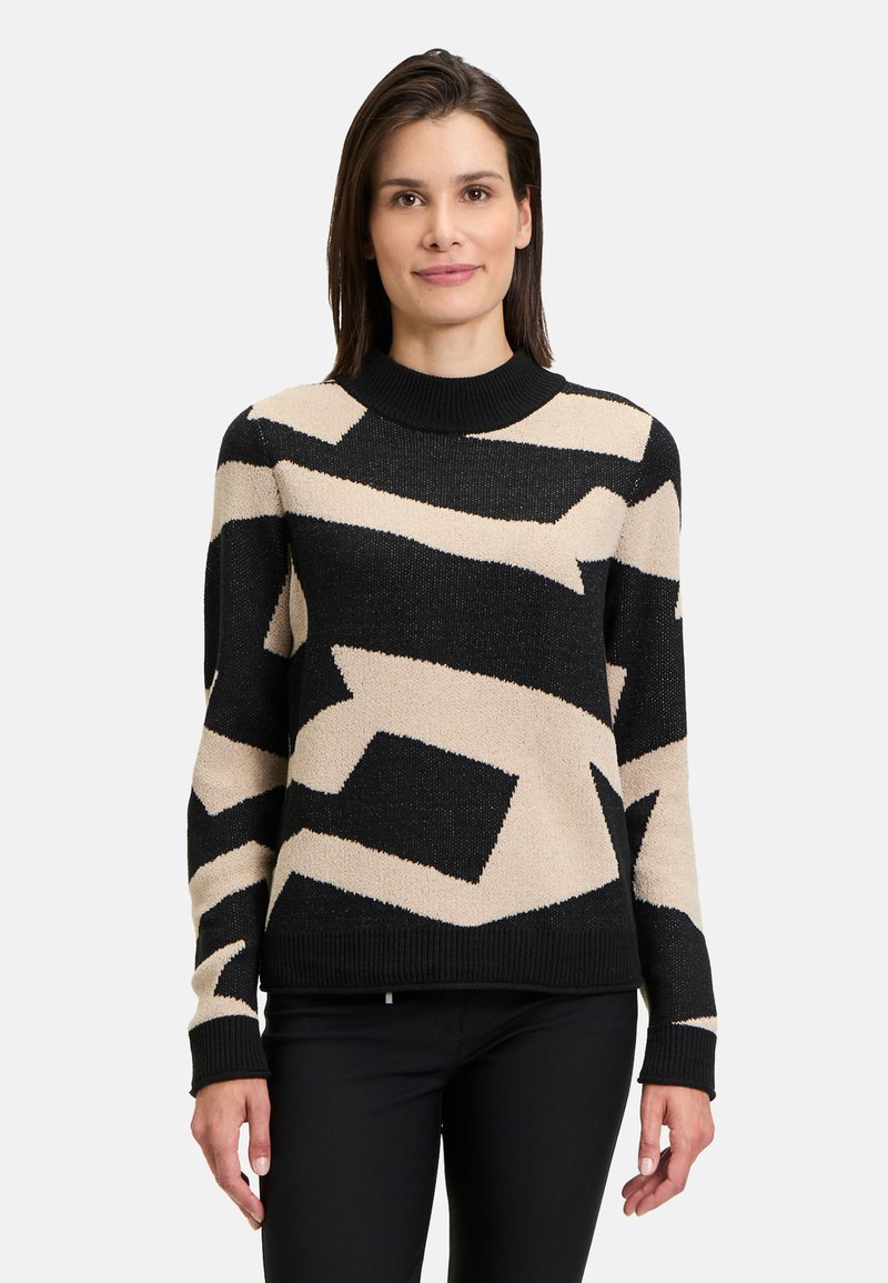 Knit sweater features a black base with beige abstract patterns, crew neck, and long sleeves. Textured fabric adds visual interest.