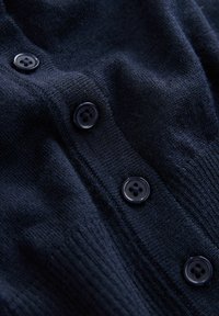Navy Strickcardigan mit strukturiertem Stoff, sechs schwarzen Knöpfen an der Vorderseite und gerippten Bündchen für eine figurbetonte Passform.