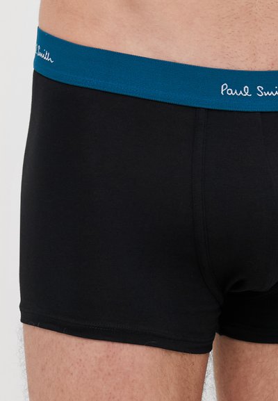 Čierne boxerské šortky s modrým elastickým pásom, na ktorom je v bielom písme "Paul Smith". Vyrobené z jemného materiálu s tesným strihom.
