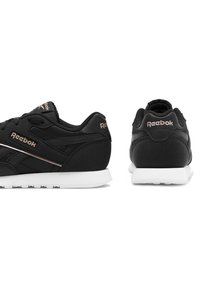 Černé tenisky Reebok s kombinací matných a hladkých textur, s bílými podrážkami a jemnými akcenty v růžovém zlatě na značkování.