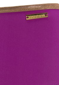 Vijolična tkaninska torba z gladko teksturo in zlatim bleščečim obrobjem na vrhu. Ima zlato kovinsko oznako logotipa pritrjeno.
