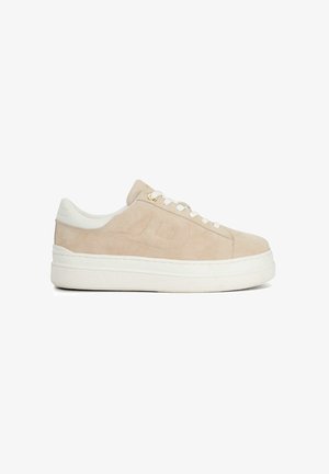 Beige suède sneaker met een witte rubberen zool, ronde neus en platte veters. Bevat minimale branding en stikselaccenten.