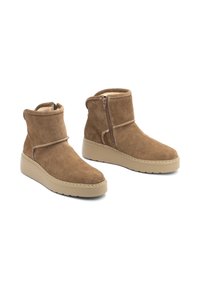 Botas de ante marrón hasta el tobillo con cierre de cremallera, que presentan una textura suave, punta redondeada y una suela gruesa beige. Detalle de costura ligera a lo largo de las costuras.