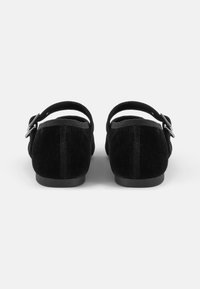 Scarpe in suede nere con tacco basso, cinturino alla caviglia e fibbia in metallo; retro arrotondato e texture liscia con dettagli di cucitura minimi.