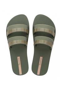 Groene rubberen slippers met twee metalen gouden golfpaternsbanden en een gestructureerde voetbed. Merkennaam 'Ipanema' op een beige streep op de zool.