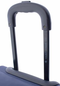 Mango telescópico negro de una maleta con un agarre texturizado y tornillos visibles, unido a una base de tejido azul marino, etiquetado como "GLADIATOR".