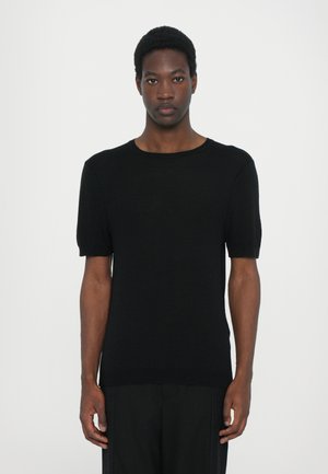 Black knit short-sleeve top with a crew neckline, featuring a smooth texture and slim fit design. The model stands against a white background.