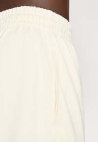 Cremefarvede træningsshorts med en tekstureret overflade, der har en elastisk Talje og sidelommer.