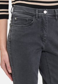 Czarne dżinsy o średnim stanie, z pięcioma kieszeniami i delikatnym zmiękczeniem. Metalowe guziki i nitki podnoszą trwałość.