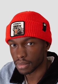 Berretto di lana rosso con una toppa quadrata che presenta un grafico di un pantera nera e la parola "FORZA". Include un accento in hardware nero.