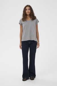 Grijze korte mouwen V-hals T-shirt gecombineerd met marineblauwe flared jeans, die een casual, relaxte pasvorm benadrukken. Textured zwarte schoenen maken de look af.