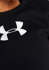 Sudadera negra con tela texturizada, con un prominente logo blanco de Under Armour en la parte delantera, cuello redondo y puños de canalé.