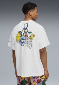 Witte katoenen T-shirt met een kleurrafiek van sleutelhangers op de achterkant, waaronder een klauw, een gamecontroller en een ananas.