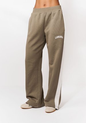 Õliveres rohelised, lahtise lõikega dressipüksid elastse vöökohaga, millel on valged küljeribad ja esiküljel valge kirjaga "LAMANIA".