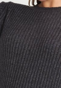 Dark gray ribbed sweater featuring a round neckline and textured fabric with subtle variations in color. Close-up view emphasizes pattern.