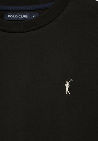 Svart polo tröja med ribbad halsringning och en liten vit broderad golfspelarlogotyp på vänster bröst. Slät, bomullstextur.