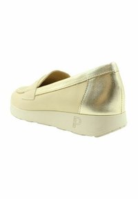 Zapato slip-on beige con un detalle metálico dorado en el tacón, fabricado en cuero suave y con una suela ligera y acolchada.