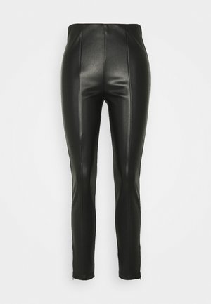 Pantalons en faux cuir noir taille haute avec détails de couture à l'avant et zips aux chevilles, style ajusté sur fond blanc uni.