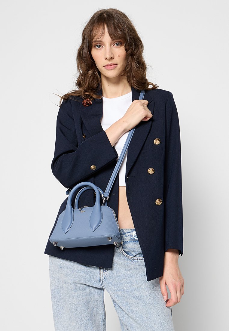 Sac à main en cuir bleu avec un design structuré, deux poignées et une bandoulière réglable, comportant des éléments en métal argenté et des accents de couture.
