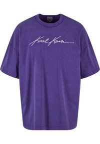 Lila bomull t-shirt med rund halsringning och korta ärmar. Har en vit stiliserad "Karl Kani" logotyp över framsidan.