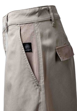 Beige cargobukse med detaljert glidelomme, klafflomme, beltehemper og svart Elias Rumelis-merkelapp.