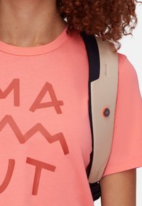 Korala t-shirt z brązowym wzorem góry; posiada beżowy pasek z pomarańczowym guzikiem; gładki materiał; luźny krój.