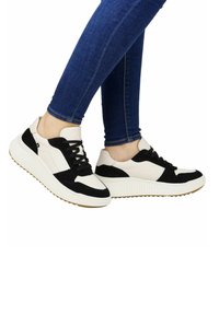 Baskets noir et blanc avec une semelle en caoutchouc, présentant un mélange de textures lisses et en daim, un design à lacets et une semelle épaisse.