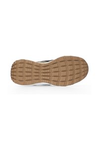 Rubber sole of a sneaker features a textured brown pattern with rectangular grips, contrasted by a white midsole and black upper.